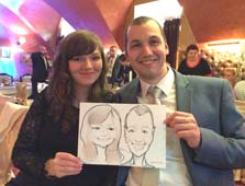 парочка показывает свой шарж по фото в ресторане Ренессанс от шаржиста